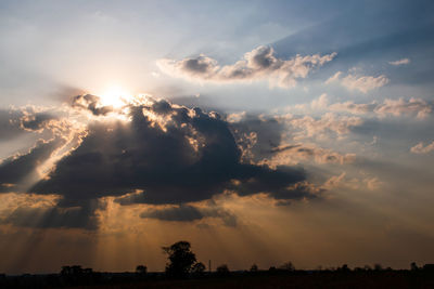 Low angle view of sunlight streaming through clouds