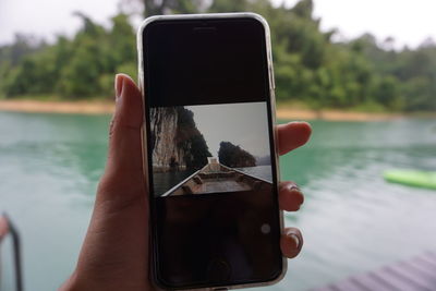 Midsection of person holding mobile phone in water