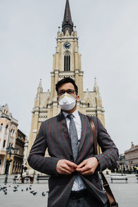 Business man standing on city street with protective face mask.