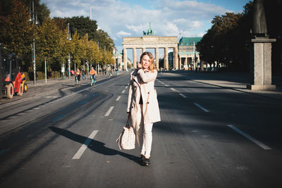 Young woman walking on road against brandenburg gate