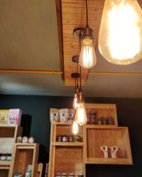 Low angle view of illuminated pendant light hanging on ceiling at home