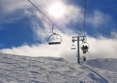 Overhead cable car on snow covered mountains against sky