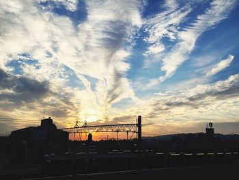 Silhouette of factory against sky