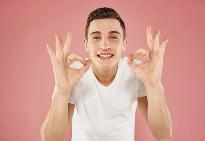 Portrait of young man gesturing against colored background