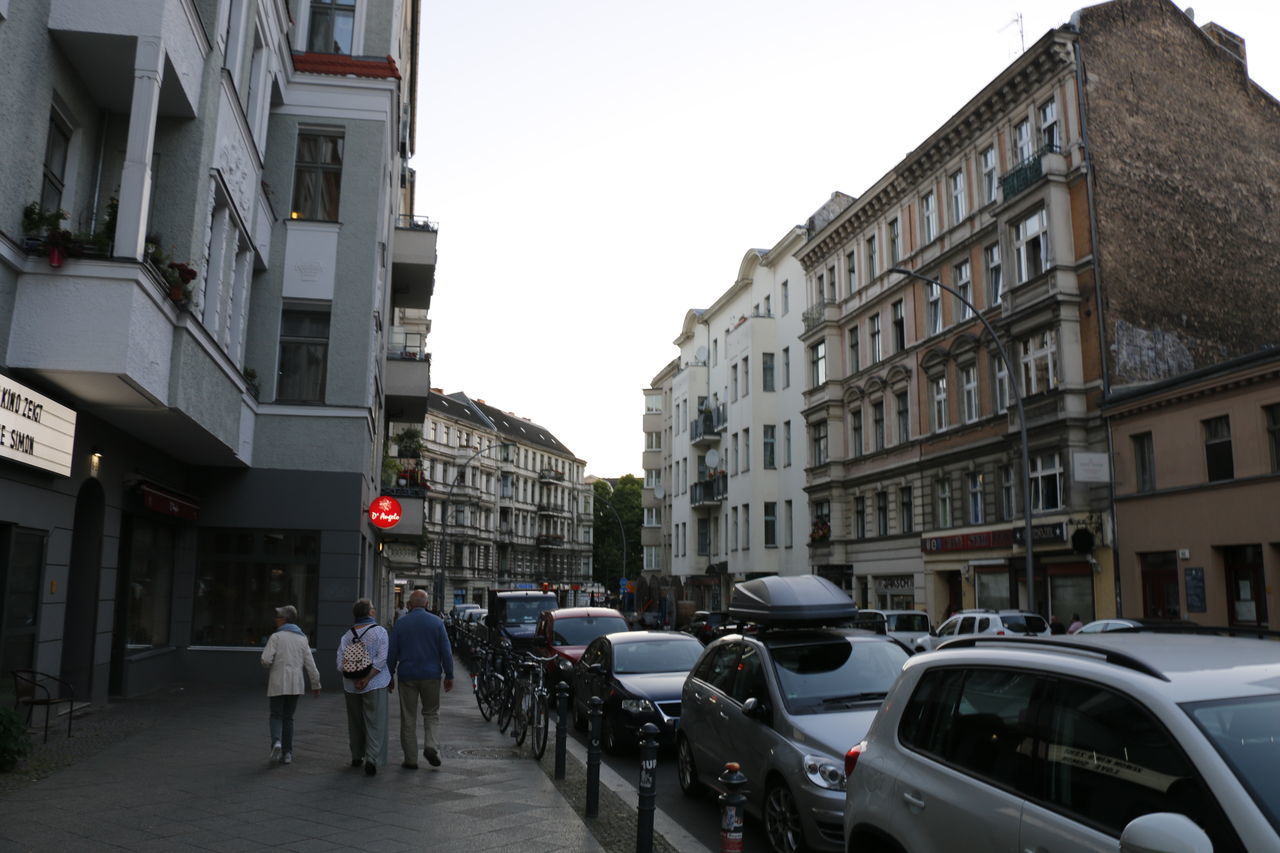 PEOPLE ON ROAD AMIDST BUILDINGS IN CITY