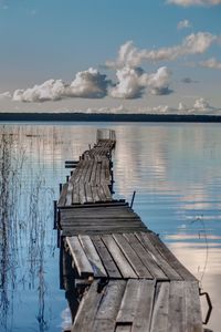 Wooden jetty on pier over lake against sky