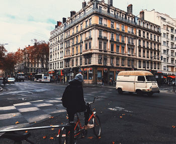 Rear view of man riding bicycle on city street