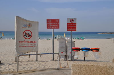 Information sign on beach against sky