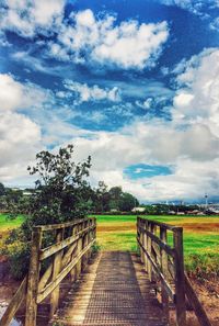 View of field against cloudy sky