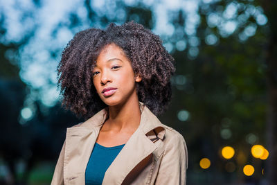 Portrait of young woman standing against trees