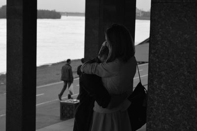 Rear view of people standing by sea