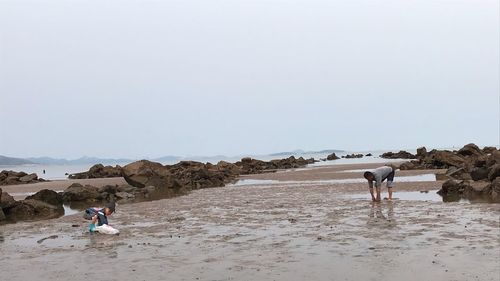 People on beach against clear sky