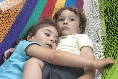 Boy relaxing with sister in hammock