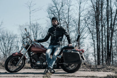 Mid adult man sitting on motorcycle in forest