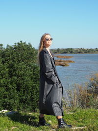 Portrait of woman standing against plants against sky