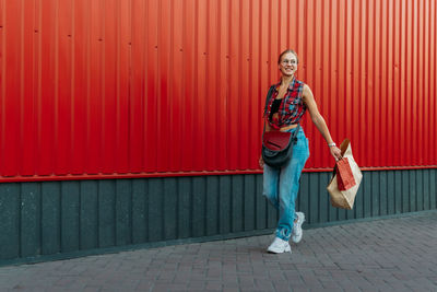 Full length of woman walking against red wall outdoors