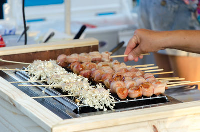 Cropped hand of person preparing food on barbeque grill