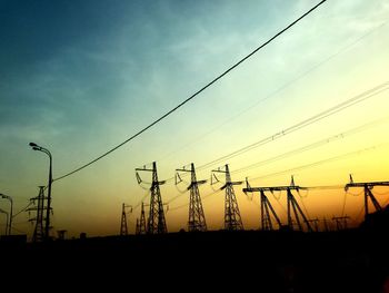 Low angle view of silhouette electricity pylon against sky during sunset