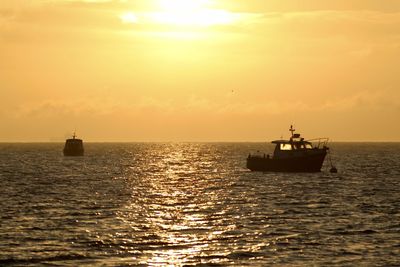 Sailboat in sea against sky during sunset