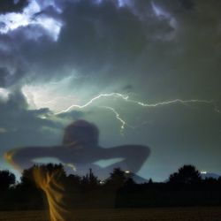Silhouette of trees on field against cloudy sky
