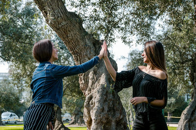 Young couple standing by tree trunk