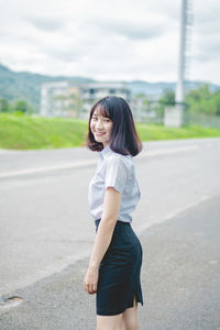 Portrait of smiling young woman standing on road