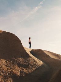 Man standing on sand dune against sky