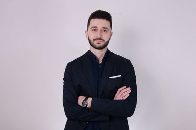 Portrait of young man standing against white background
