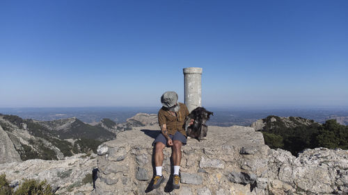 A hiker on the top of a mountain with his pet. outdoor activities. travel with dog