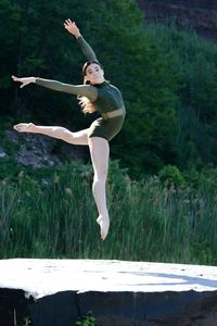 Full length of woman jumping against plants