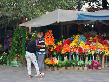 Rear view of people standing by flowering plants