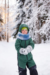 Portrait of boy wearing hat standing on snow covered land