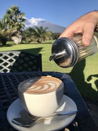 Midsection of person pouring coffee in cup on table