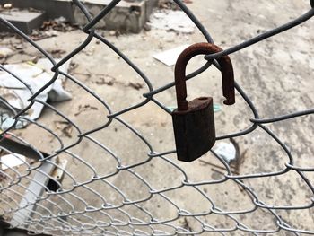 Close-up of rusty padlock on chainlink fence