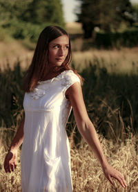 Beautiful woman standing amidst plants on field