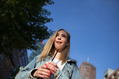 Shocked woman holding disposable cup in city