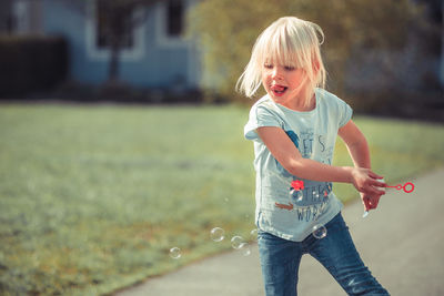 Girl playing with bubble wand while standing at park