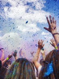 Close-up of people playing with powder paint against sky