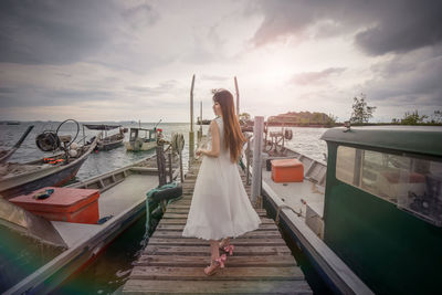 Rear view of woman standing on boat against sky