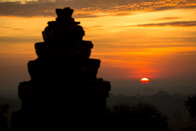 Silhouette of statue against cloudy sky during sunset