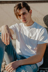 Portrait of young man sitting on wall