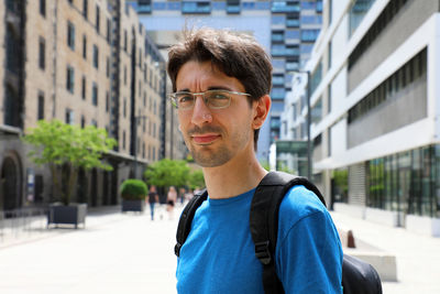 Portrait of young man standing against city