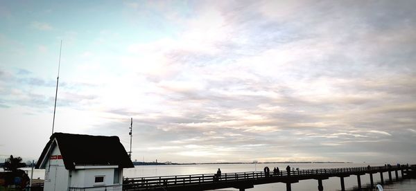 Silhouette bridge over sea against sky during sunset