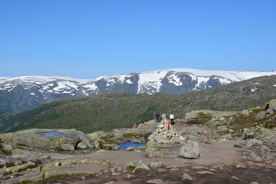 People on mountain peak against clear blue sky