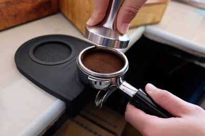 Cropped image of hand fixing portafilter at coffee shop