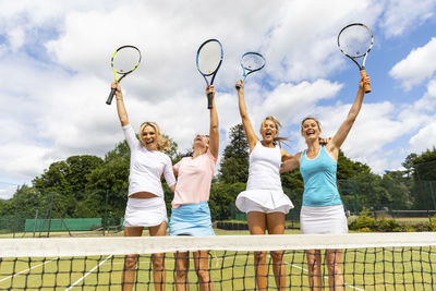 Happy female tennis players celebrating the victory on grass court