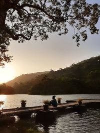 Silhouette people on lake against sky during sunset