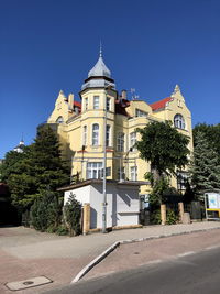 Building by road against clear blue sky