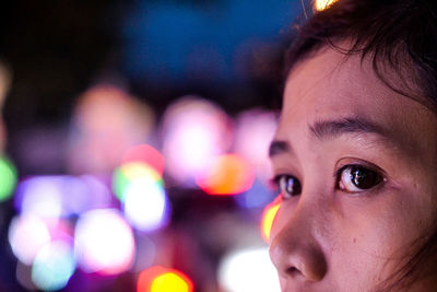 Close-up of woman against illuminated lights at night