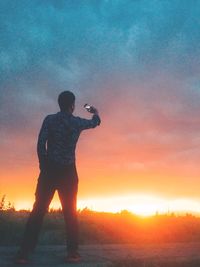 Silhouette man standing against orange sky during sunset